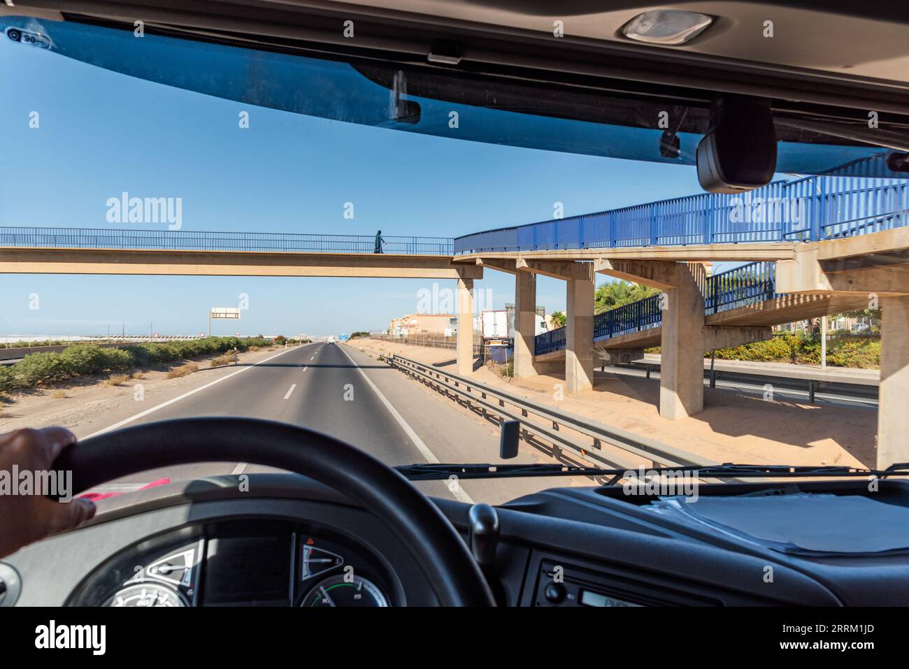 View from the driving position of a truck of a pedestrian walkway where a person crosses on a highway. Stock Photo