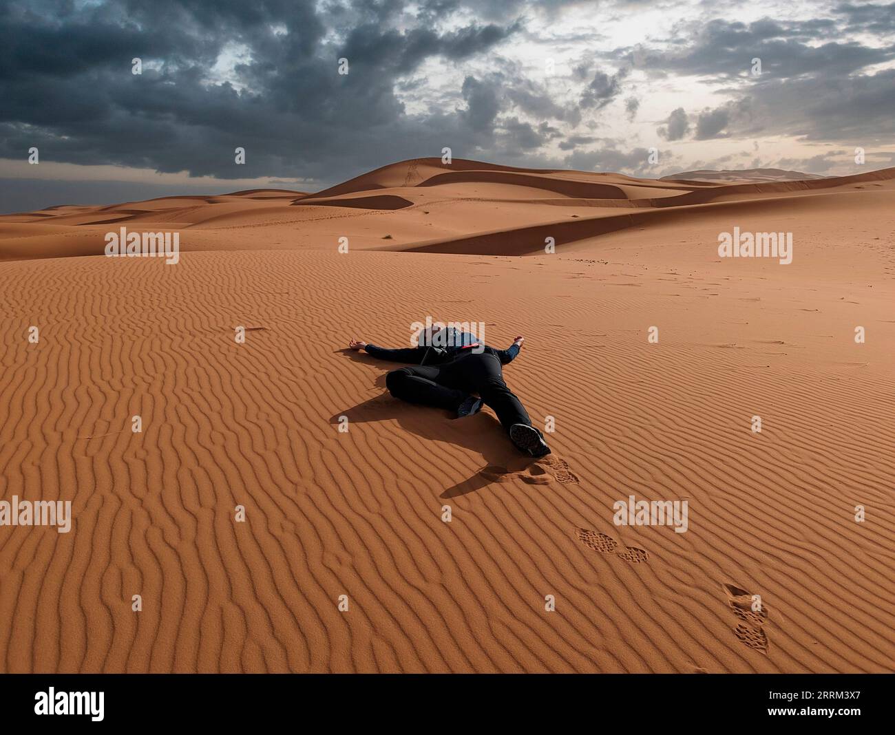 A person pretending to lay dead in the Erg Chebbi desert in Morocco Stock Photo