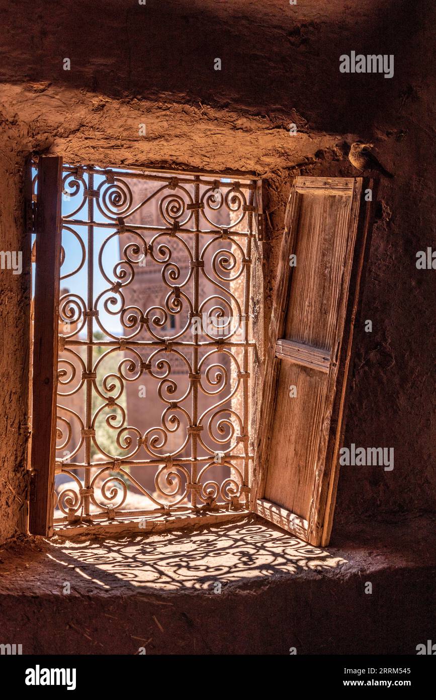 An ornate window grid and derelict wooden shutters at a typical Moroccan kasbah Stock Photo