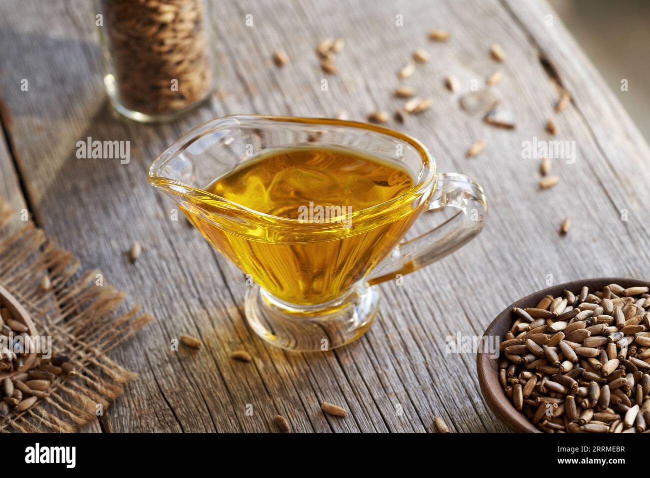 A jug of milk thistle oil with Carduus marianus seeds on a wooden table Stock Photo