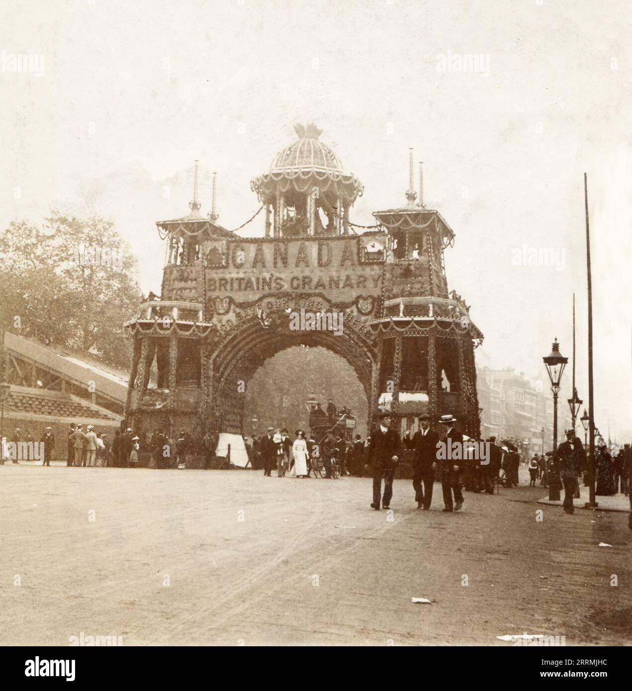 London. 1902 – A busy street scene depicting the Canadian Arch, in Whitehall, London. The arch was erected on the ceremonial route from Buckingham Palace to Westminster Abbey, for the coronation of King Edward VII in July 1902. It was illuminated, and decorated with both wheat sheaves from Manitoba and maple leaves. It bore the caption, “Canada – Britain’s Granary – God Save Our King & Queen”. Stock Photo