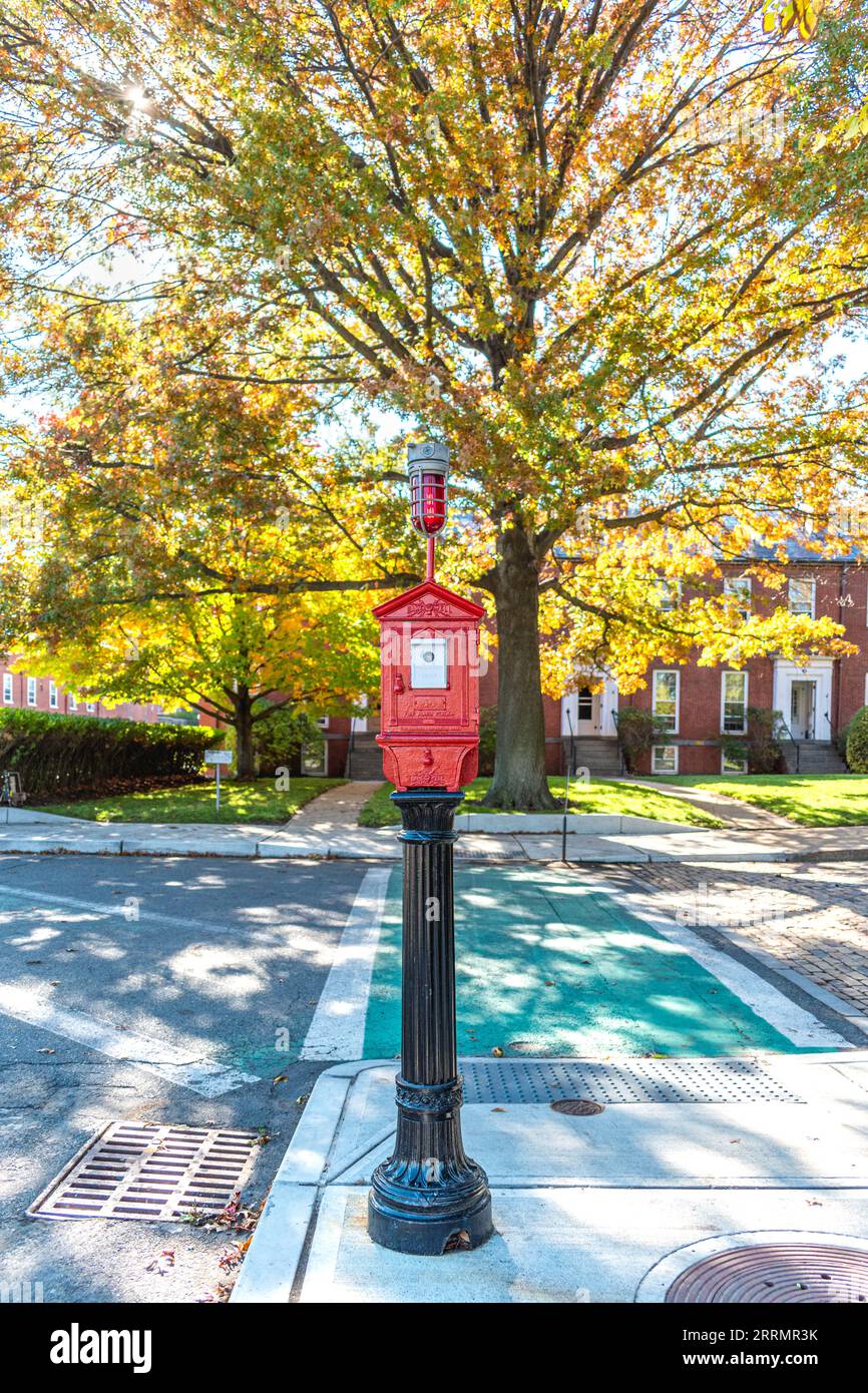 Traditional Boston fire alarm station box - manufactured by Game Well - on a pedestal in front of beautiful fall trees on a sunny fall day Stock Photo