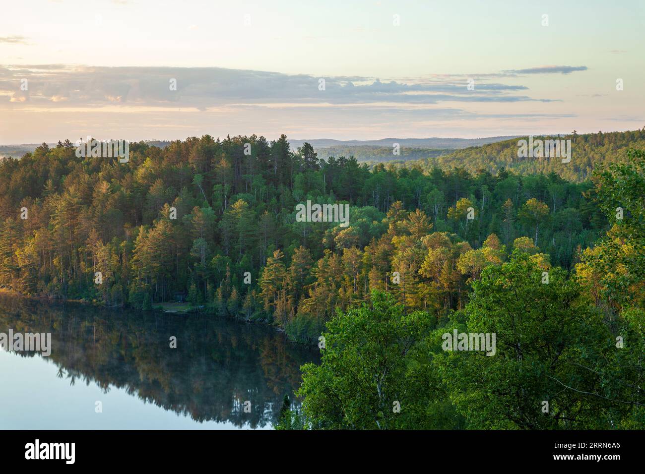 Trees on hills at dawn by a calm lake near the Gunflint Trail in northern Minnesota during summer Stock Photo