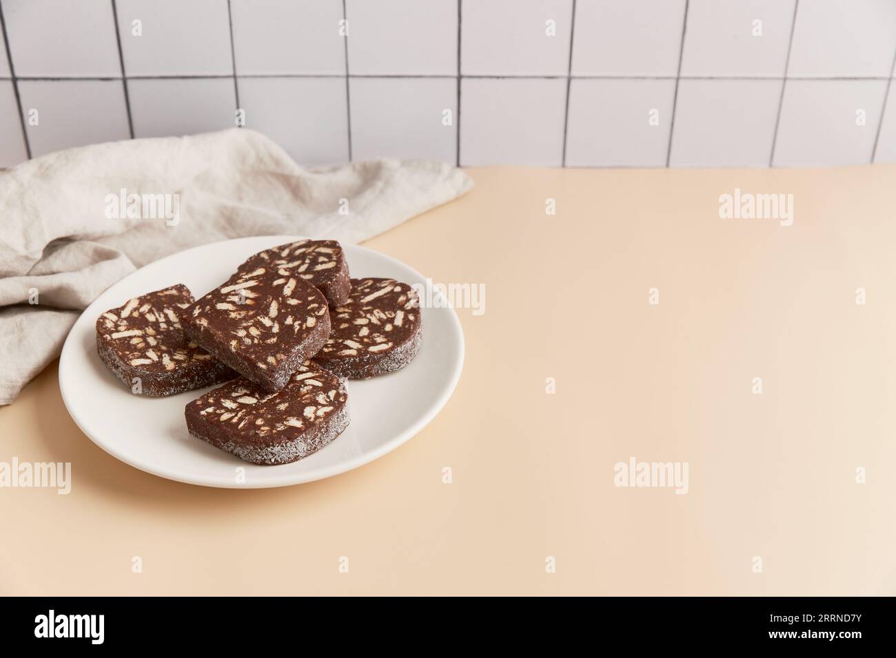 Traditional portuguese dessert Salame de Chocolate on beige background in minimal style. Homemade cocoa cake. Stock Photo