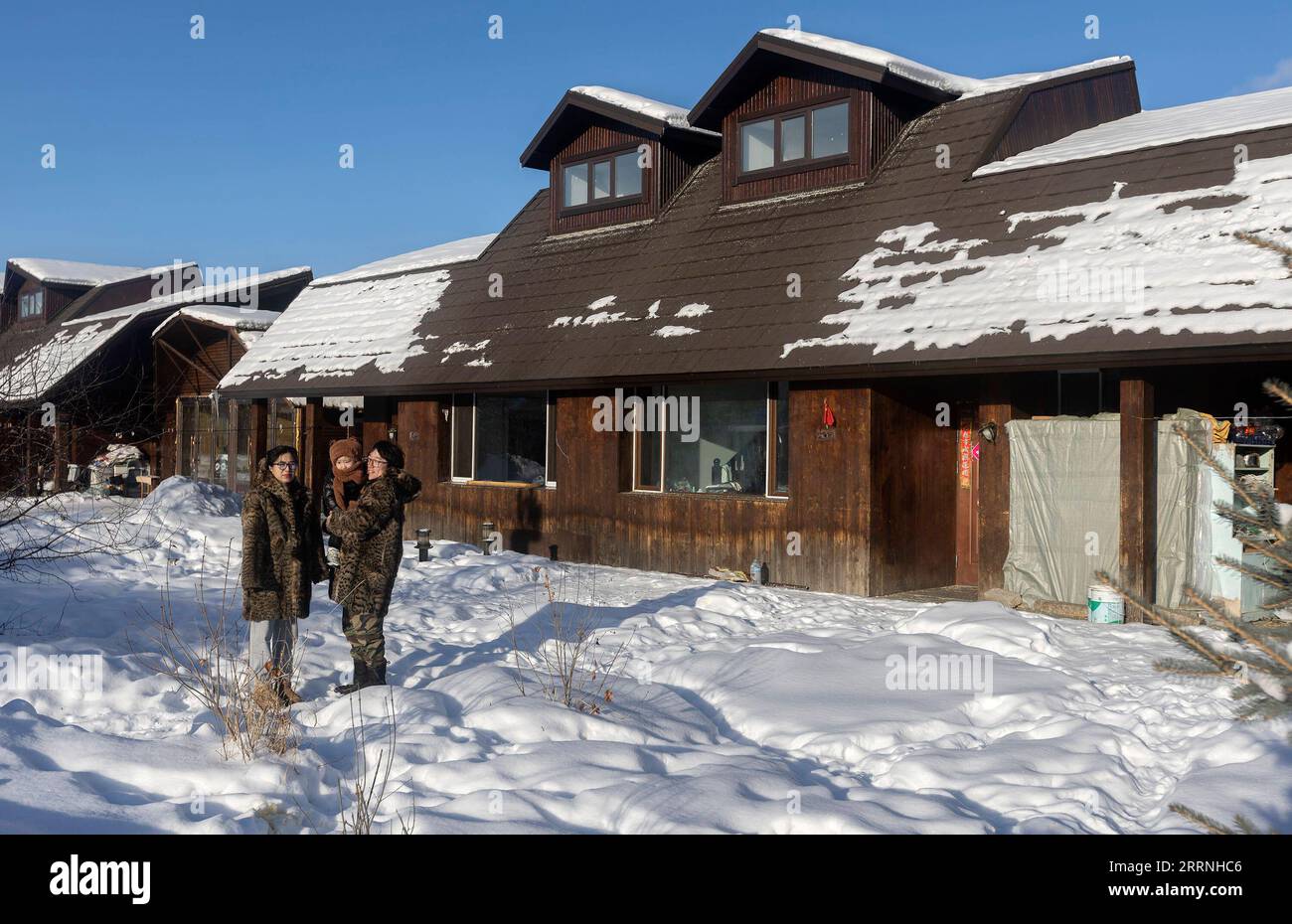 230113 -- GENHE, Jan. 13, 2023 -- This photo taken on Jan. 13, 2023 shows Juele with his family at a new relocation community in Aoluguya Ewenki Township, Genhe City of north China s Inner Mongolia Autonomous Region. Every two or three days, Juele Bulituotian will head for the Jinhe forest range about 80 kilometers from Genhe City. That s where the 39-year-old Aoluguya Ewenki herder, wearing a traditional fur coat, will find his foraging reindeer. Instead of keeping reindeer in a barn, Ewenki herders let the animals live in the forest and check on them every couple of days. Juele owns over 60 Stock Photo