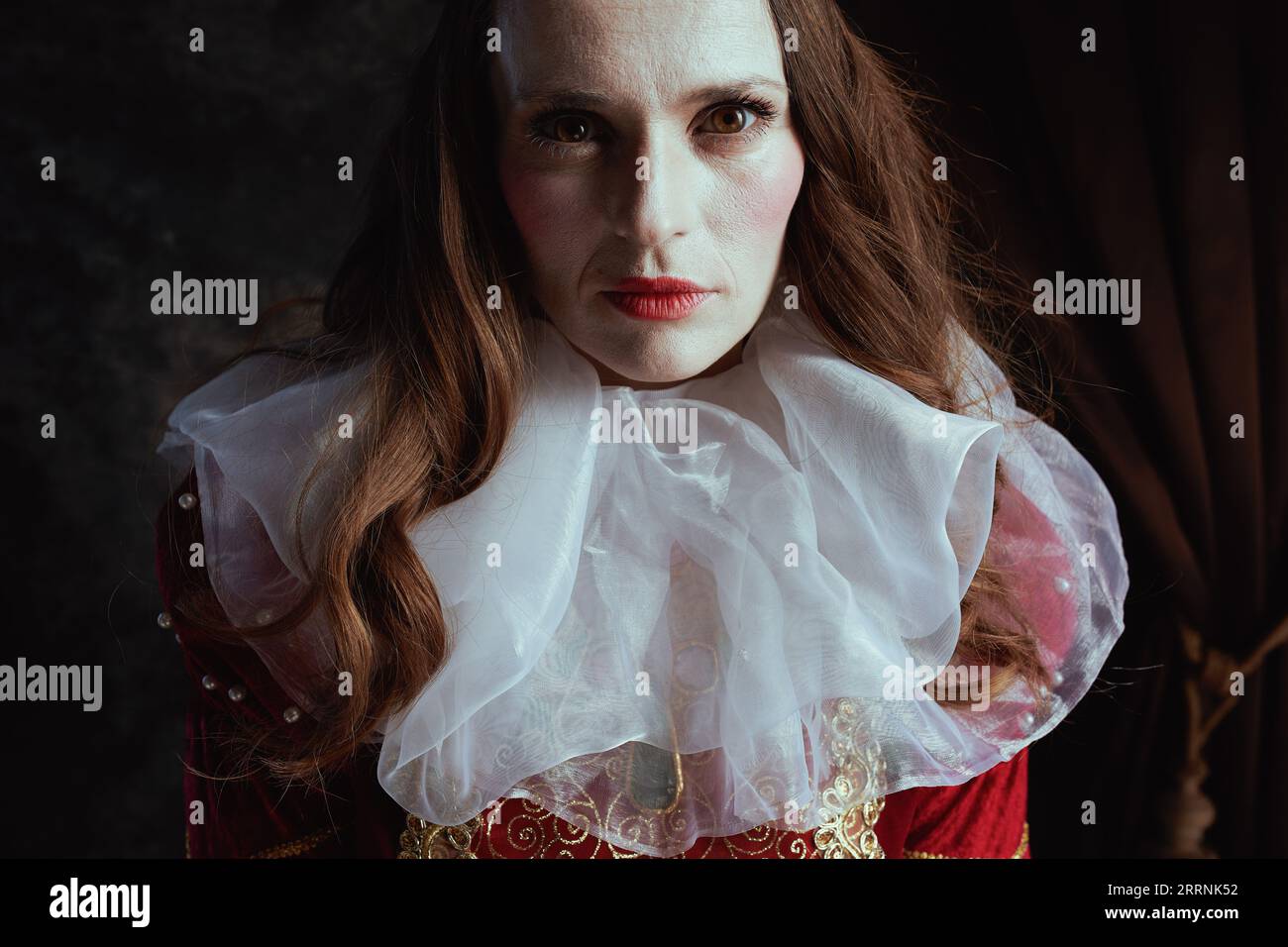 medieval queen in red dress with white collar on dark gray background ...