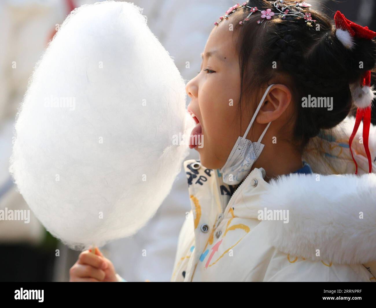 230124 -- TENGZHOU, Jan. 24, 2023 -- A girl eats cotton candy in Xigang Township of Tengzhou, east China s Shandong Province, Jan. 22, 2023. People enjoy various kinds of cuisine in China during the Spring Festival holiday. Photo by /Xinhua CHINA-SPRING FESTIVAL-CUISINE CN LixZhijun PUBLICATIONxNOTxINxCHN Stock Photo
