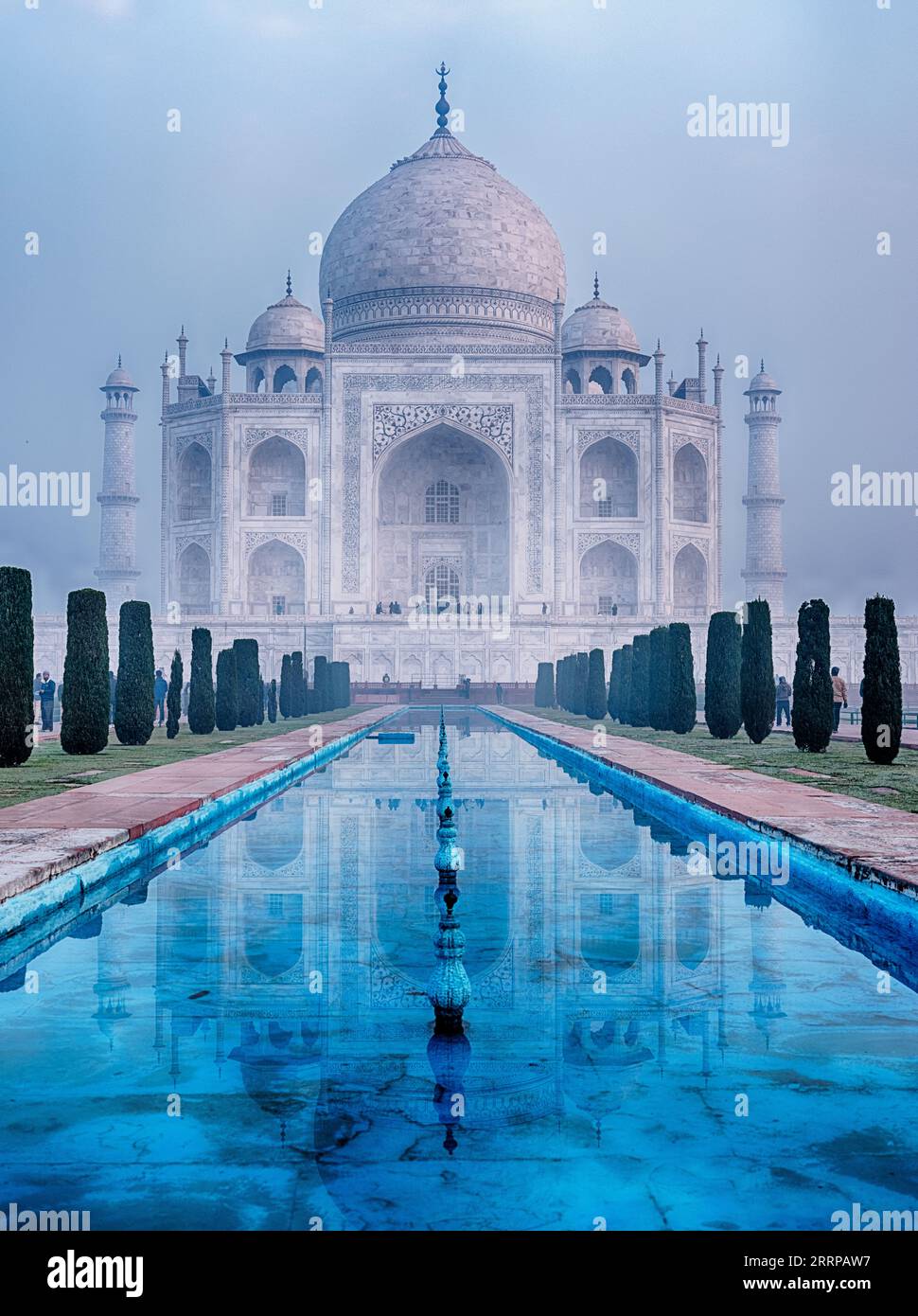On a misty morning, the reflecting pool leads towards the Taj Mahal in Agra. Stock Photo