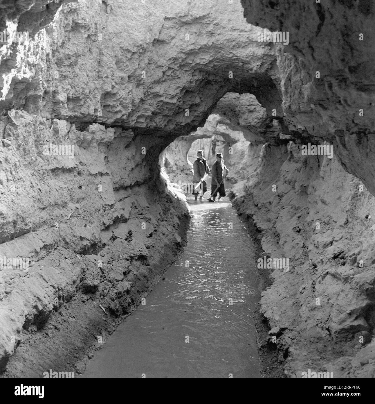 230320 -- URUMQI, March 20, 2023 -- This file photo taken on May 9, 1963 shows local farmers checking the conditions of water flow along an underground channel in Turpan, northwest China s Xinjiang Uygur Autonomous Region. Located at the southern foot of the Tianshan Mountains, Turpan in Xinjiang Uygur Autonomous Region is one of the driest and hottest places in China, with an average annual precipitation of only 16 millimeters and evaporation of up to 3,000 millimeters. In order to make this vast Gobi into a comfortable and livable oasis, the local people found new way as water reserve in kar Stock Photo