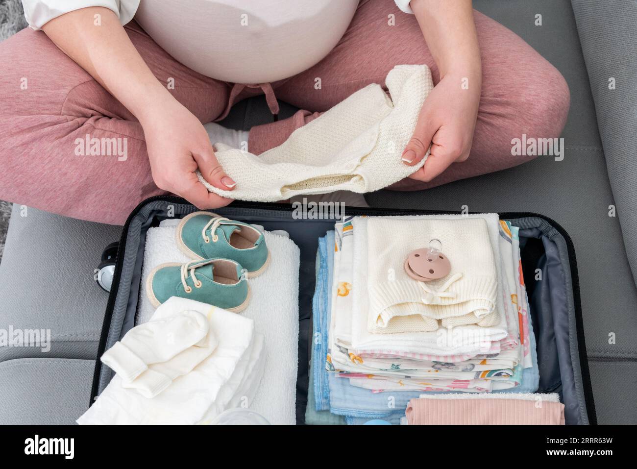 Anticipating the birth journey, pregnant woman meticulously packing