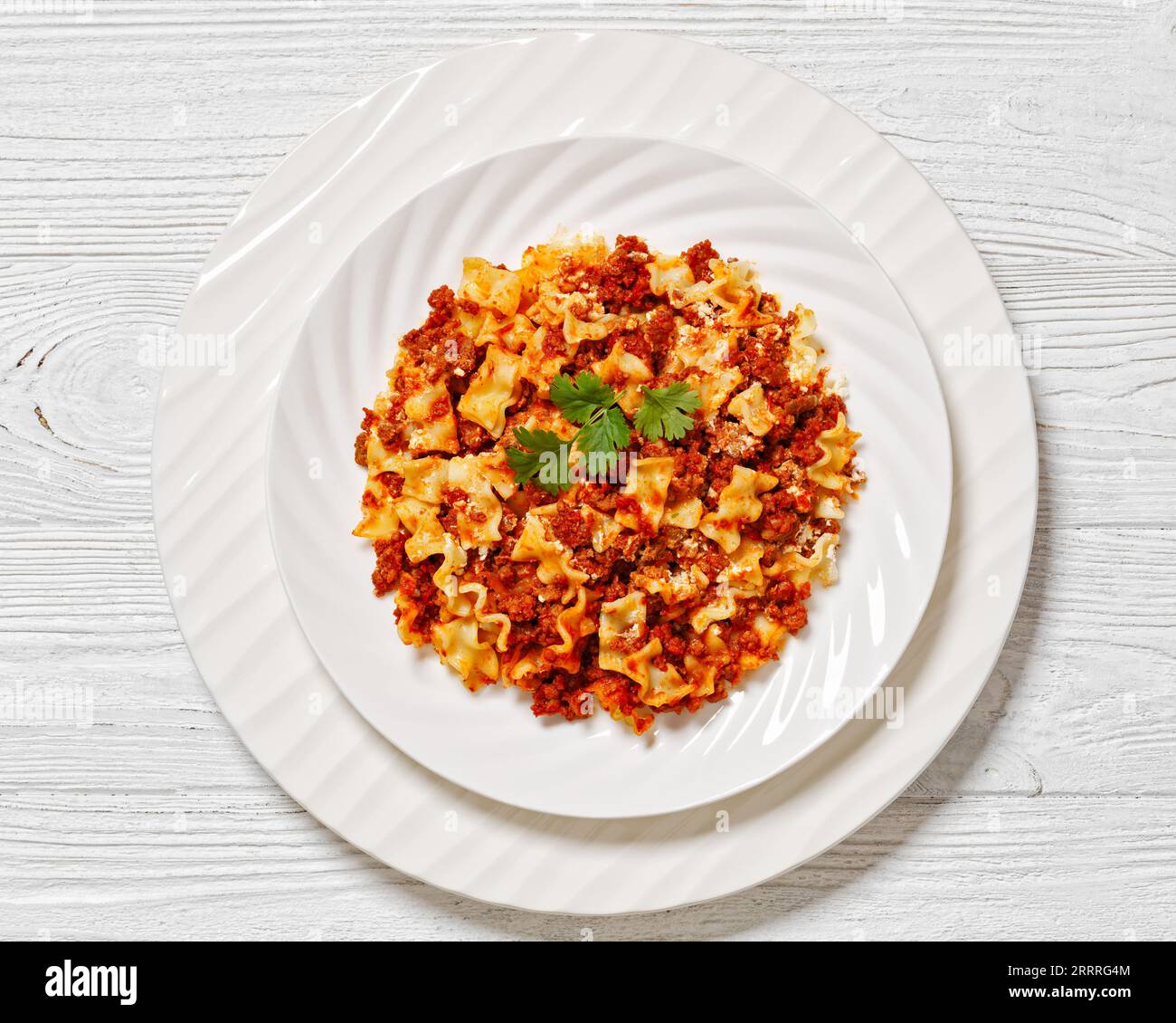 bolognese with ground beef, tomatoes, ricotta and cheese on white plate on white