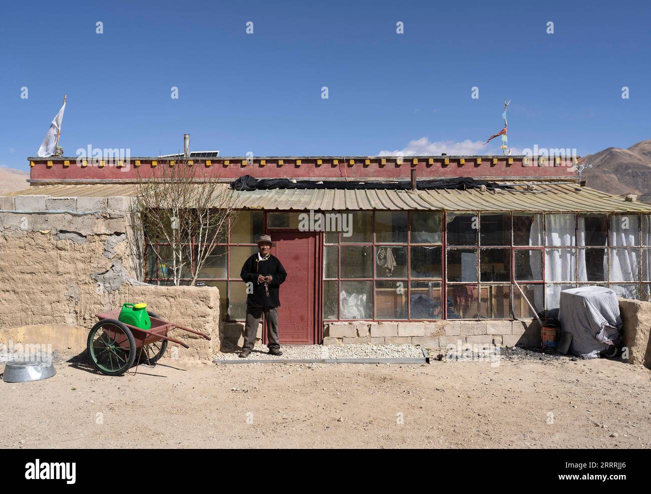 230531 -- NGARI, May 31, 2023 -- Losang Zhamdu poses for photos in front of his fourth residence, or one of the third-generation houses, in Demqog Village, Zhaxigang Township, Gar County in Ngari Prefecture of southwest China s Tibet Autonomous Region, May 28, 2023. Sitting in the sun outside his residence in Demqog Village, Zhaxigang Township, Gar County in Ngari Prefecture of Tibet, 84-year-old Losang Zhamdu told a story of the five homes he had lived in. My mother and I lived together in a tent made with yak hair, all our possessions were a goat fur jacket and a worn-out Tibetan blanket, re Stock Photo