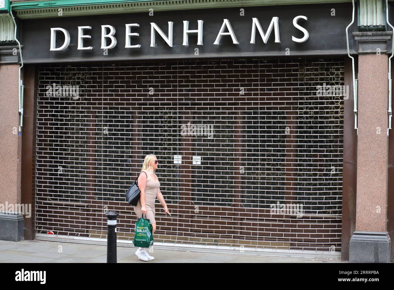 A woman walks past a closed Debenhams outlet store in Oxford, UK Stock Photo