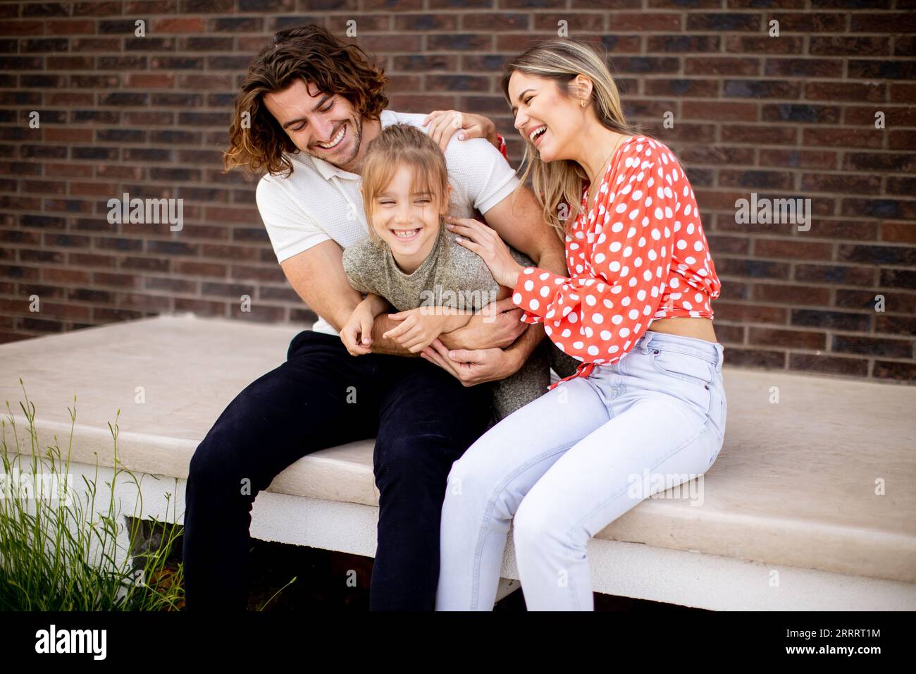 Family with a mother, father and daughter sitting outside on steps of a