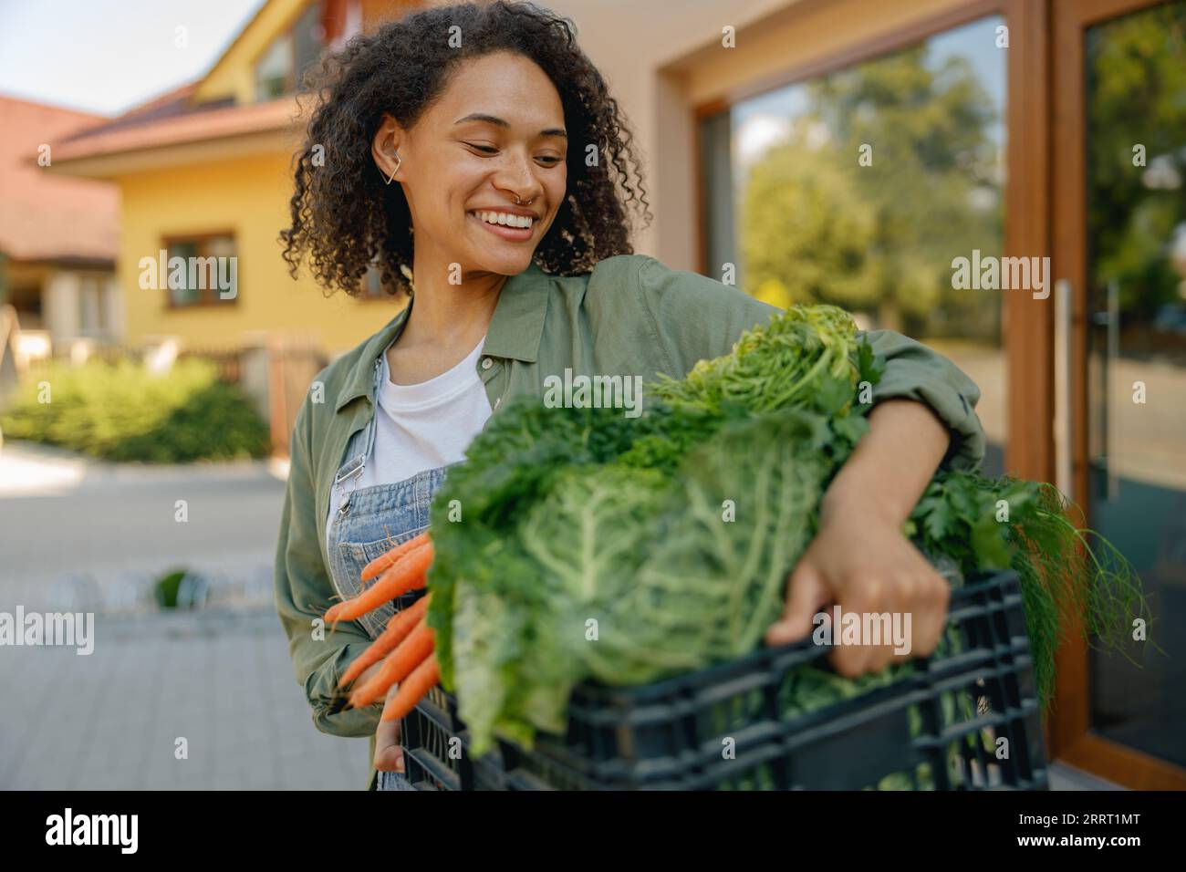 Smiling woman farmer with just harvested vegetables basket ready to ...