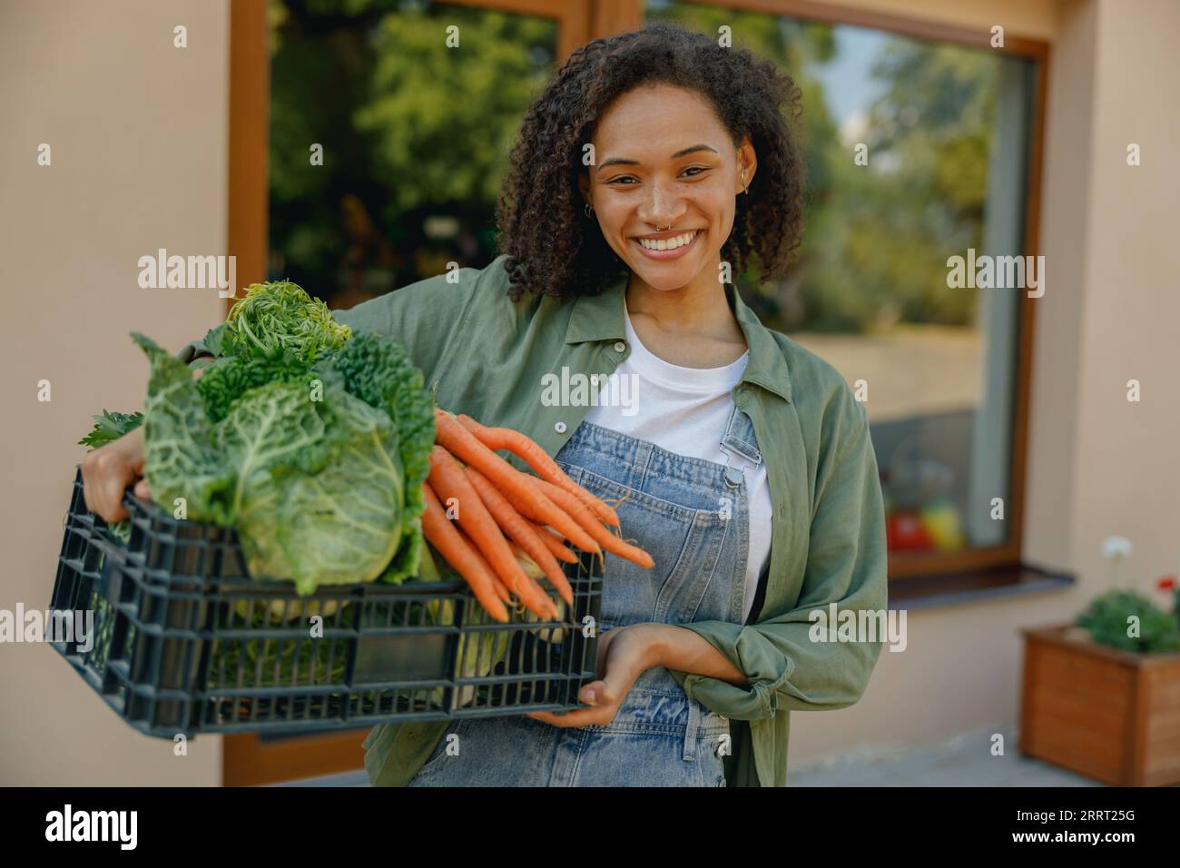 Smiling woman farmer with just harvested vegetables basket ready to ...