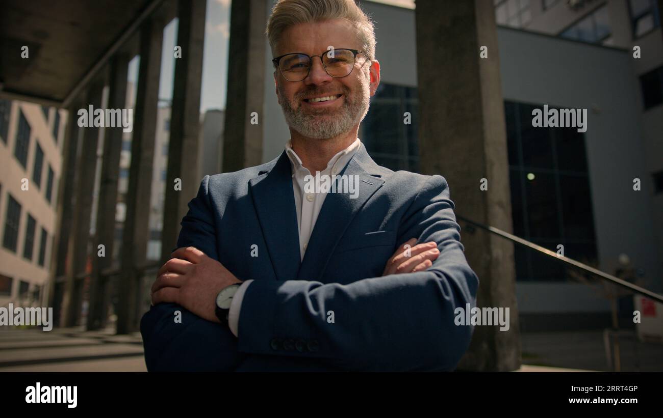 Close up business portrait outdoors in city middle-aged Caucasian man businessman toothy smiling at camera office company center building outside Stock Photo