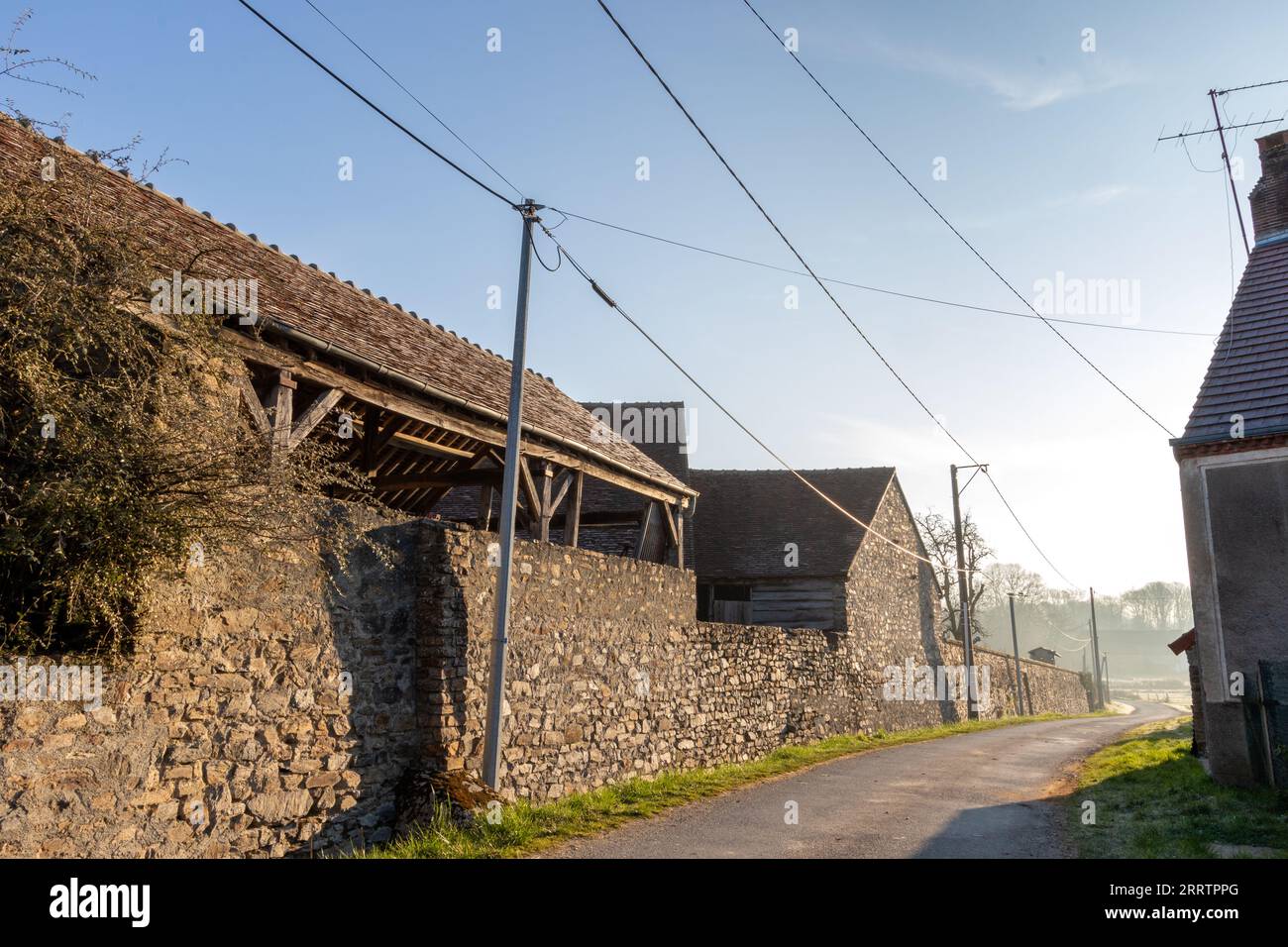 A Street view of Lignaud, Lourdoueix-Saint-Pierre, in La Creuse at dawn with stone buildings and a misty background. Stock Photo