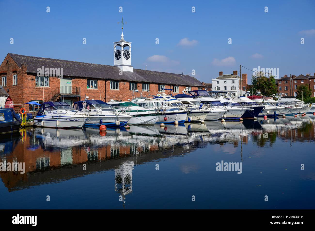 A row of GRP river and canal cruisers moored up in the canal basin in Stourport upon Severn in front of the Stourport Yacht Club building. Stock Photo