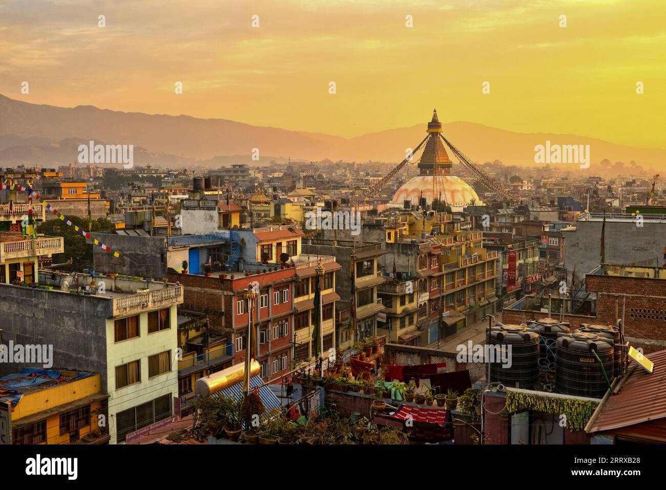Bouddha, the Great stupa in Kathmandu and buildings around in Kathmandu, Nepal, in a smoggy orange sunset hue Stock Photo