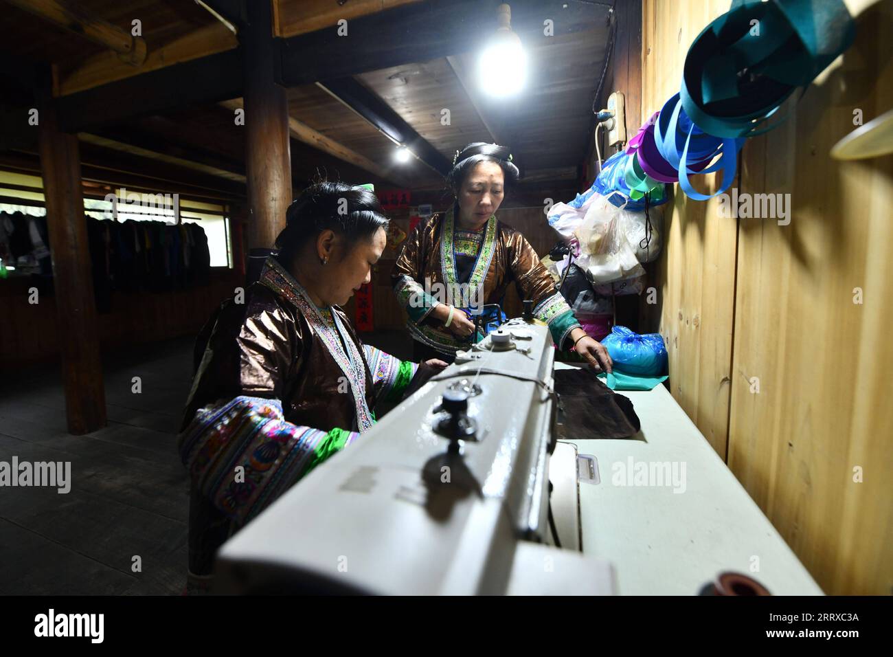 230903 -- RONGSHUI, Sept. 3, 2023 -- Liang Zuying R and Wu Meiqiu sew Liang Bu costumes in Wuying Village on the border between south China s Guangxi Zhuang Autonomous Region and southwest China s Guizhou Province, on Aug. 31, 2023. Wuying Village is a Miao ethnic group hamlet that nestles snugly in the towering mountains stretching across the border between Guangxi and Guizhou. Liang Bu , named for its glistening appearance, is a kind of traditional hand-made cloth of Miao ethnic group. Women of Miao ethnic group in Wuying plant woad in spring and harvest it in fall. They soak woad in water f Stock Photo