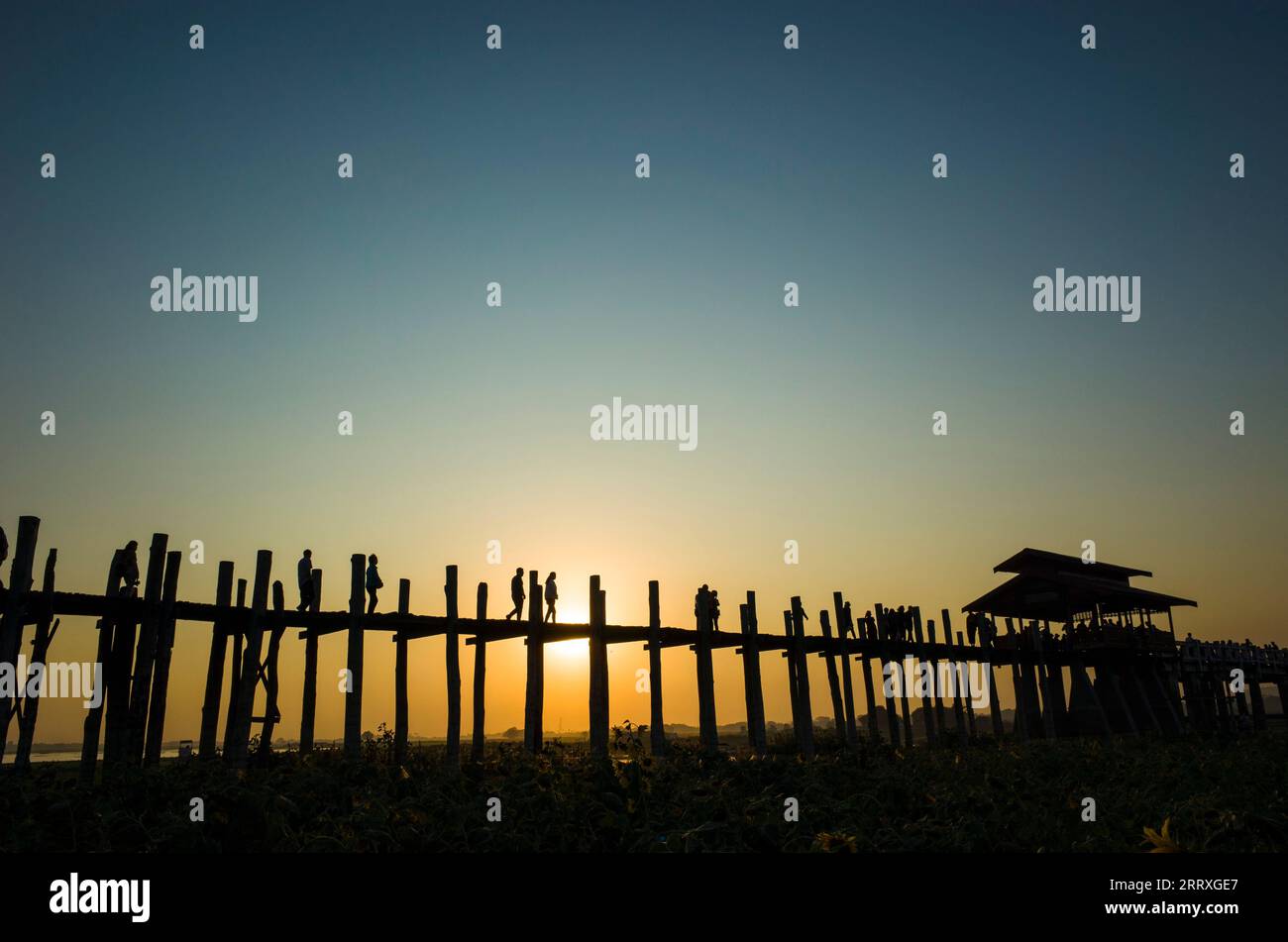 Silhouette of U bein bridge at sunset with sunrays shining under bridge ...