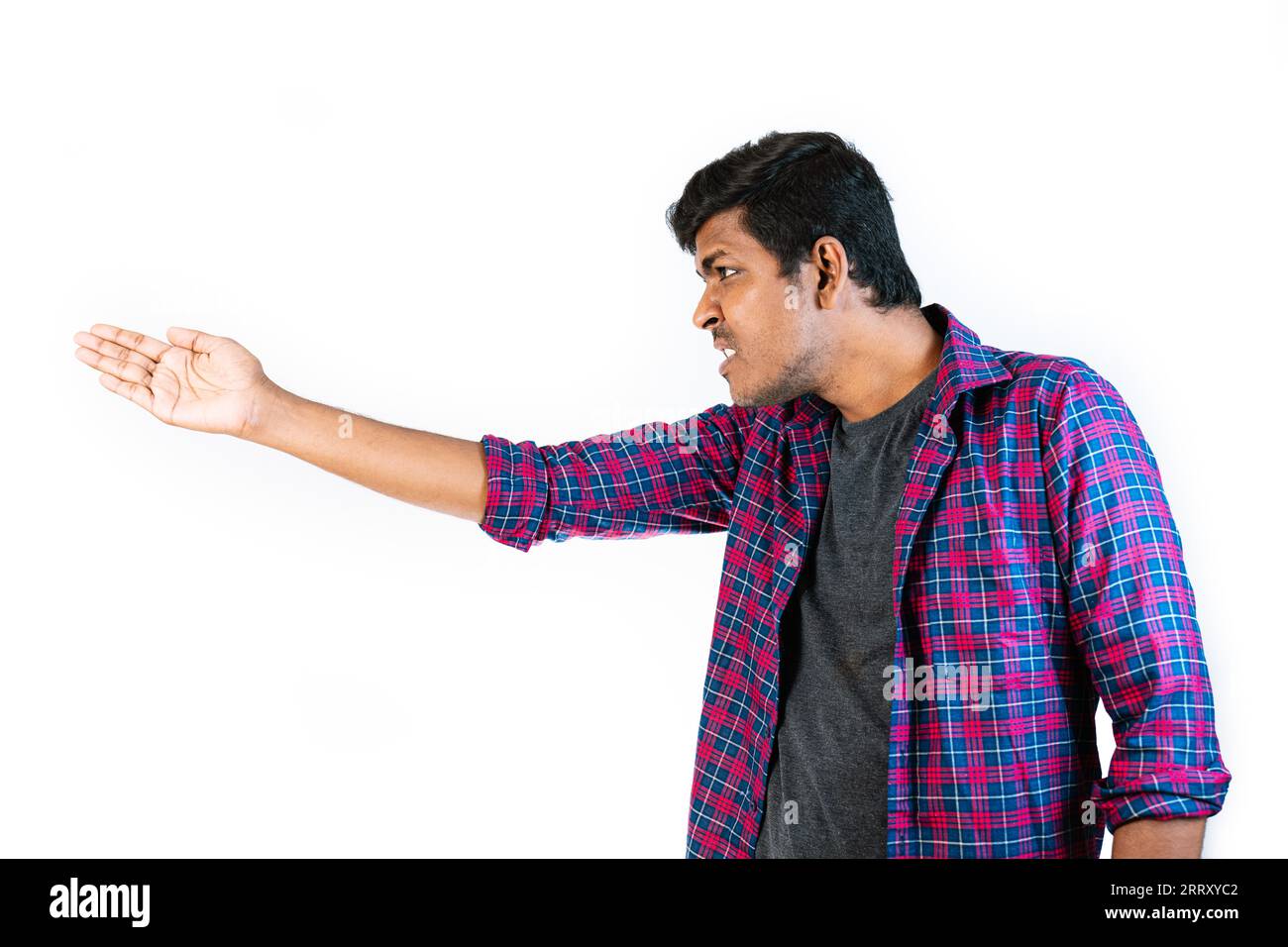 A young man is making an angry gesture against a plain background. He ...