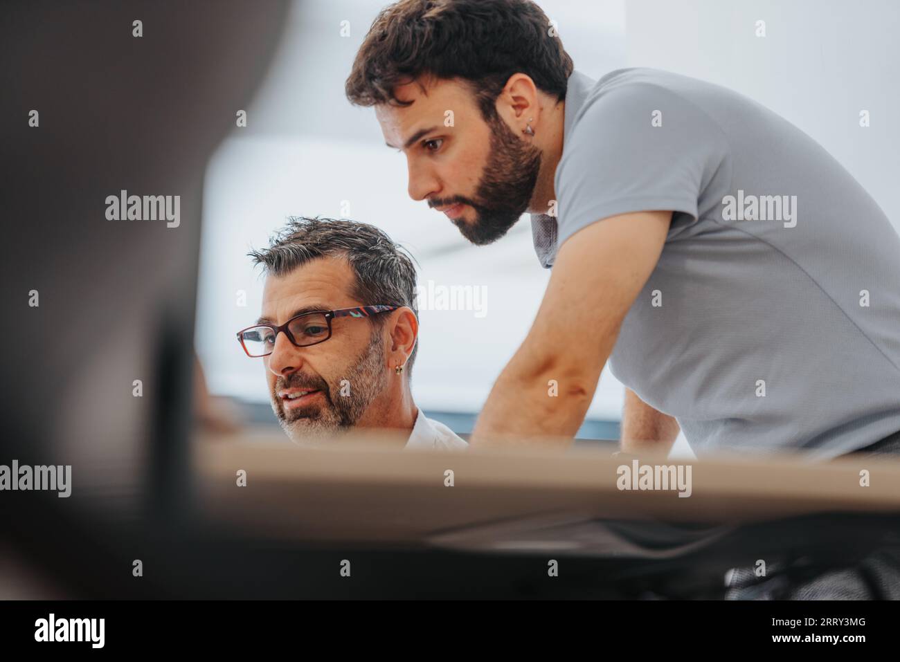 Confident business professionals analyzing reports in a diverse office, utilizing technology for data analysis. Efficient team focused on problem-solv Stock Photo