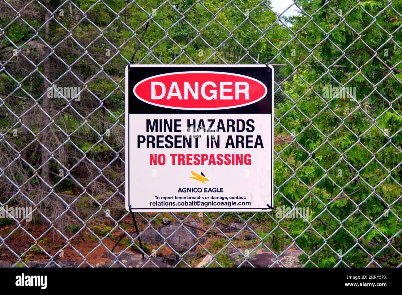 Sign posted on a fence warning people to keep out as there are hazards on the property because it was an old mining site. Stock Photo