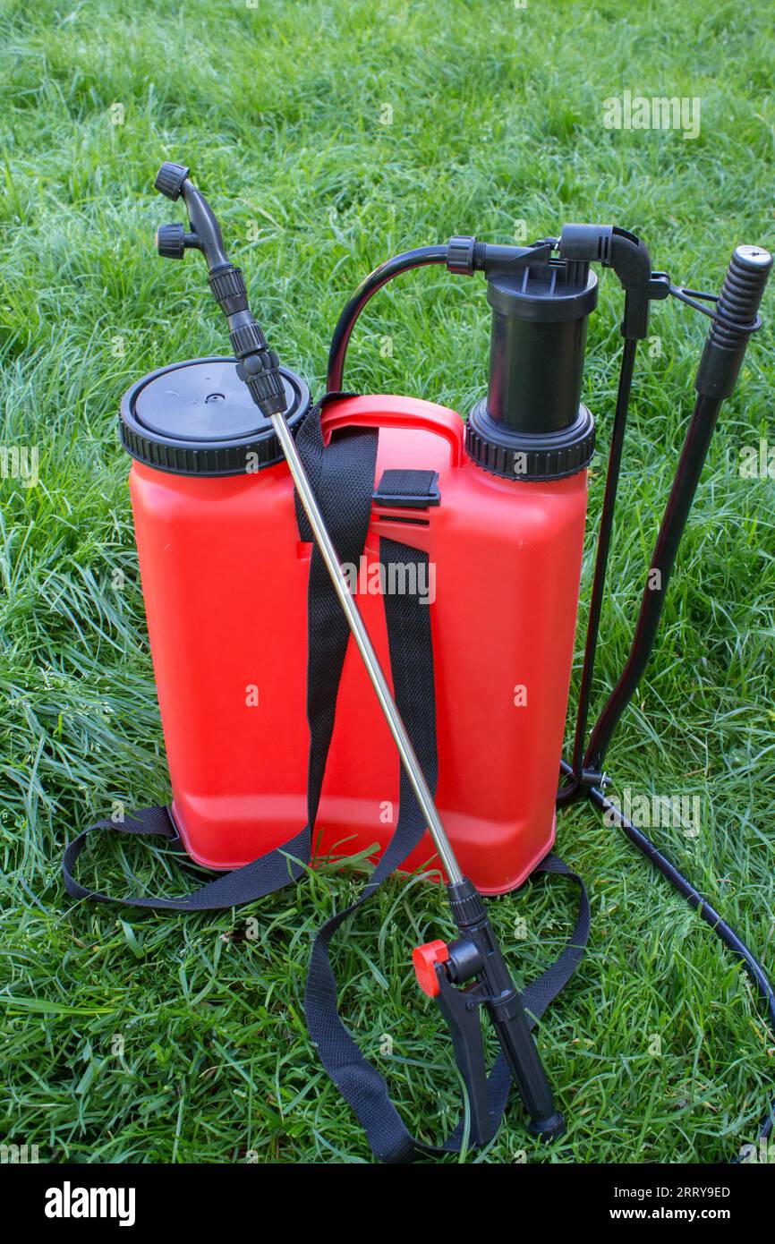 On the grass there is a red garden sprayer for the farm Stock Photo