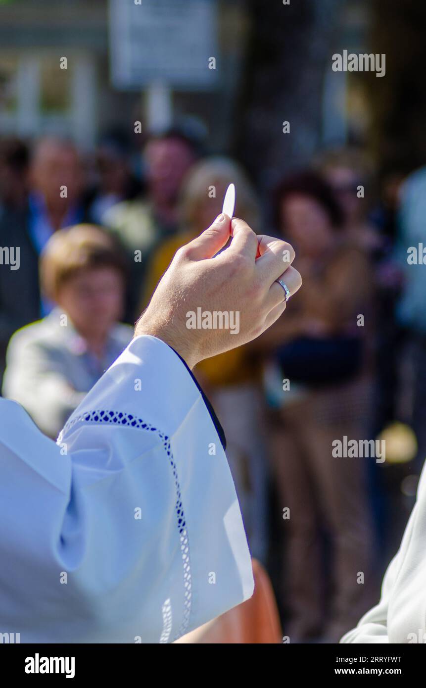 Hand of a catholic priest holding a host during the eucharist Stock