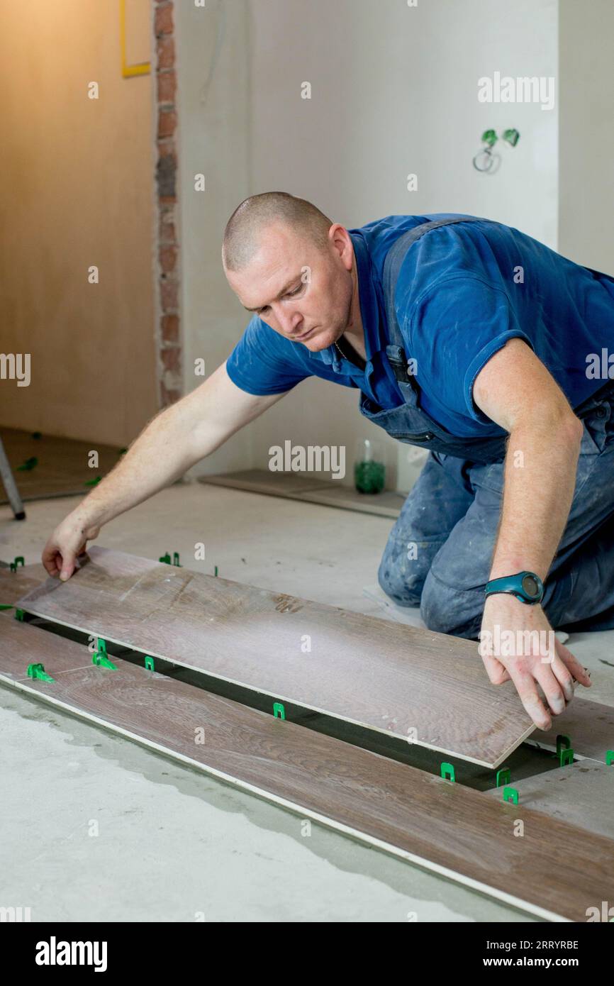 Tiler placing ceramic wall tile in position over adhesive with lash tile  leveling system. Ceramic Tiles Stock Photo - Alamy
