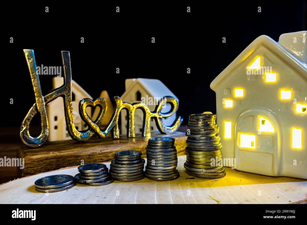 home price increase concept illustration  metal home sign with coins and ceramic houses with light buying house from an agent Stock Photo