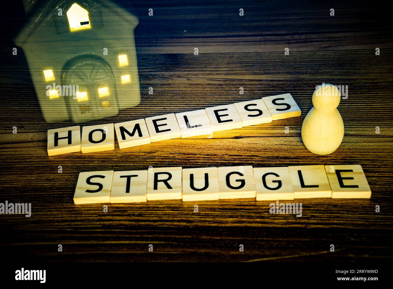 homeless struggle in wooden letters on a wood background, a figure with vanishing house Stock Photo
