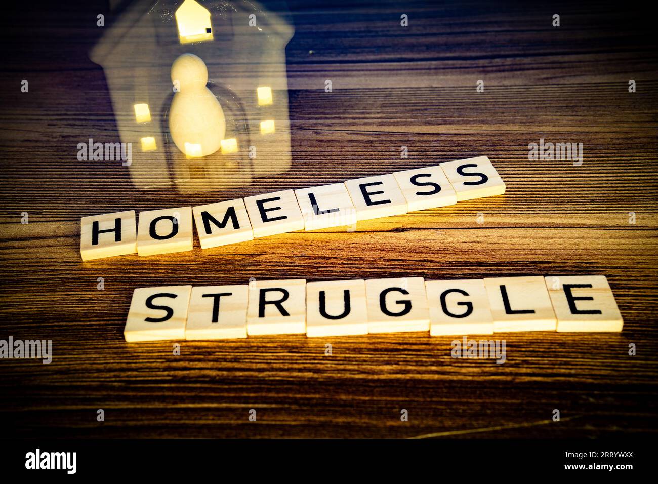 homeless struggle in wooden letters on a wood background, a figure in vanishing house Stock Photo