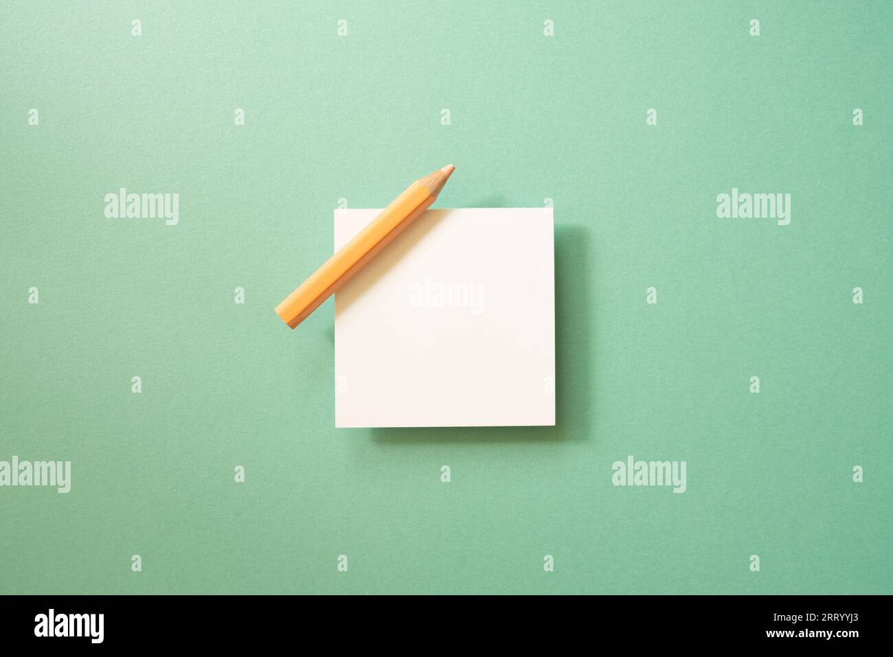 White memo paper, sticky note pad with colored pencil on green background. top view, copy space Stock Photo