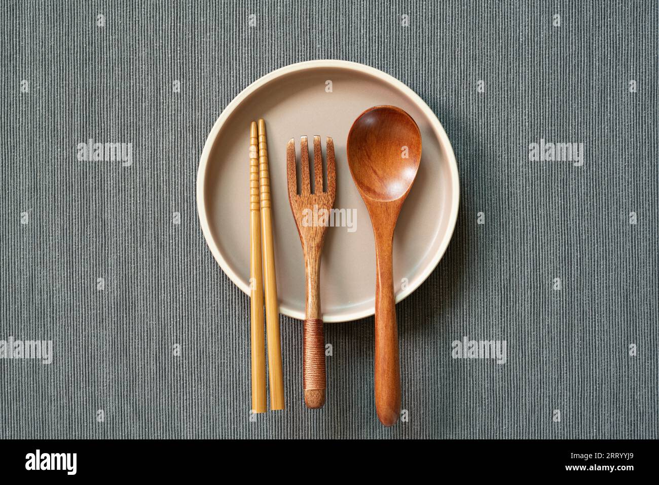 Kitchenware. dish, wooden spoon, fork, chopsticks on gray fabric background. top view, copy space Stock Photo