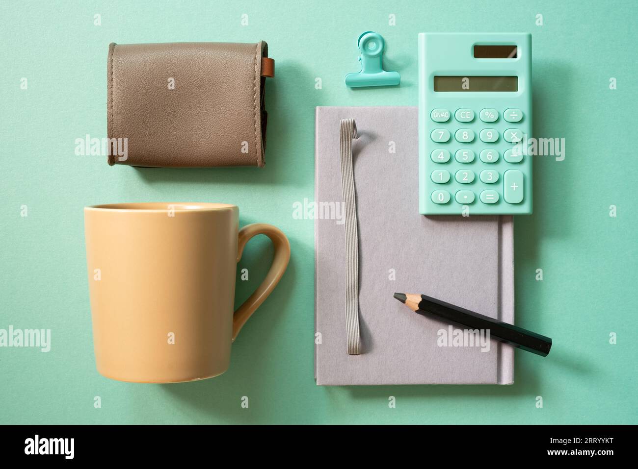Notebook, calculator, clip, mug cup, pouch on green desk background. flat lay, top view. workspace Stock Photo
