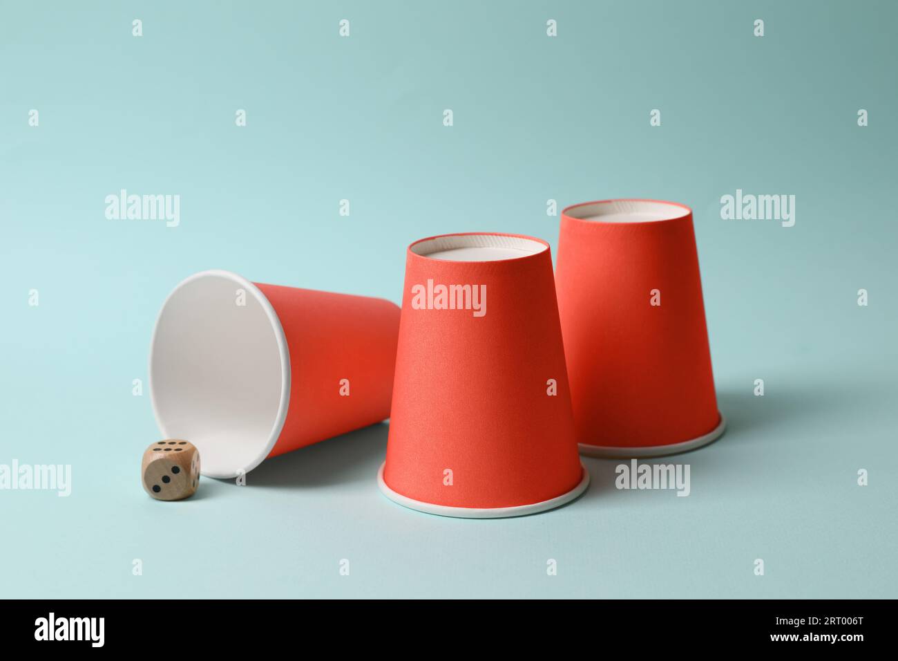 Three red cups and dice on light blue background. Thimblerig game Stock ...