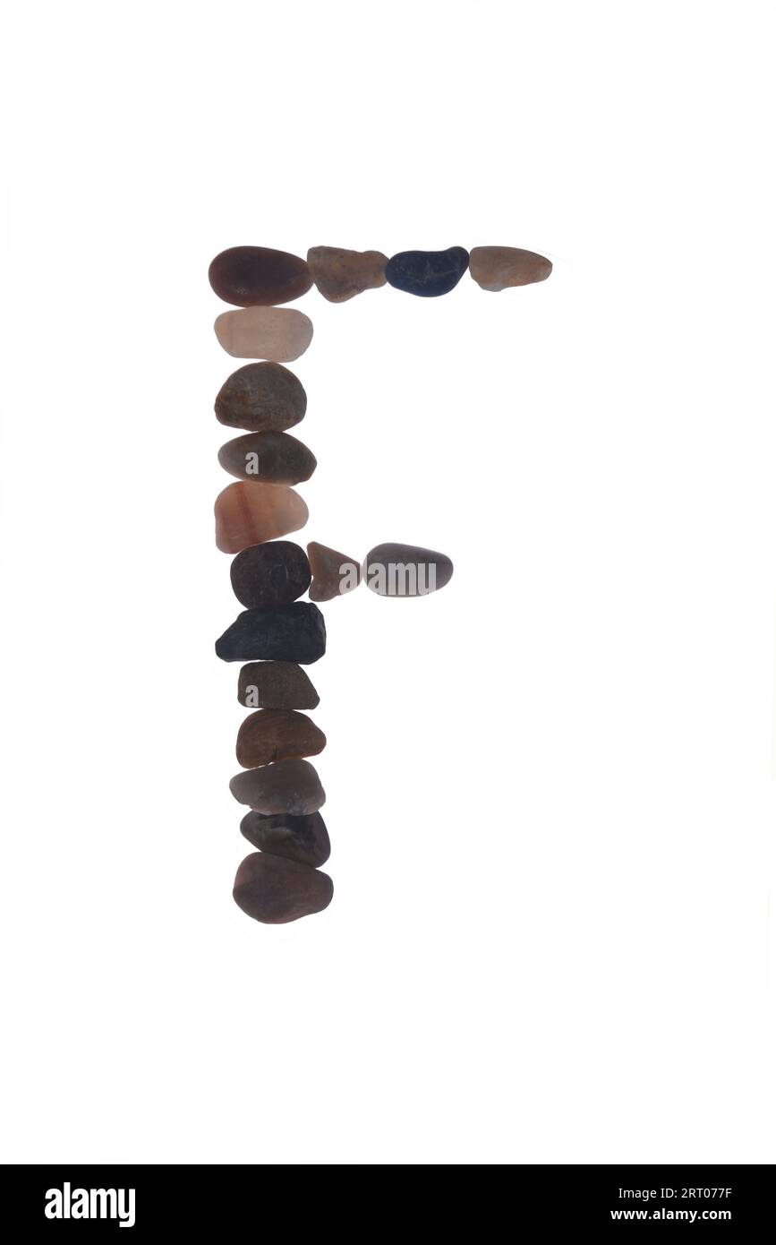 Letter F handcrafted  using small stones or pebbles, single object. creating artistic impact meaning to your message, on white background. Stock Photo