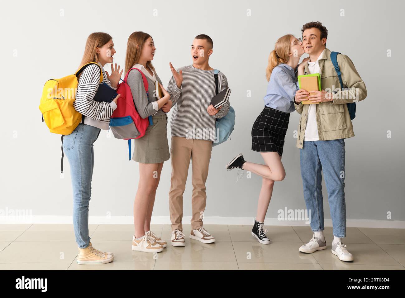 Group of students and their kissing friends near grey wall Stock Photo