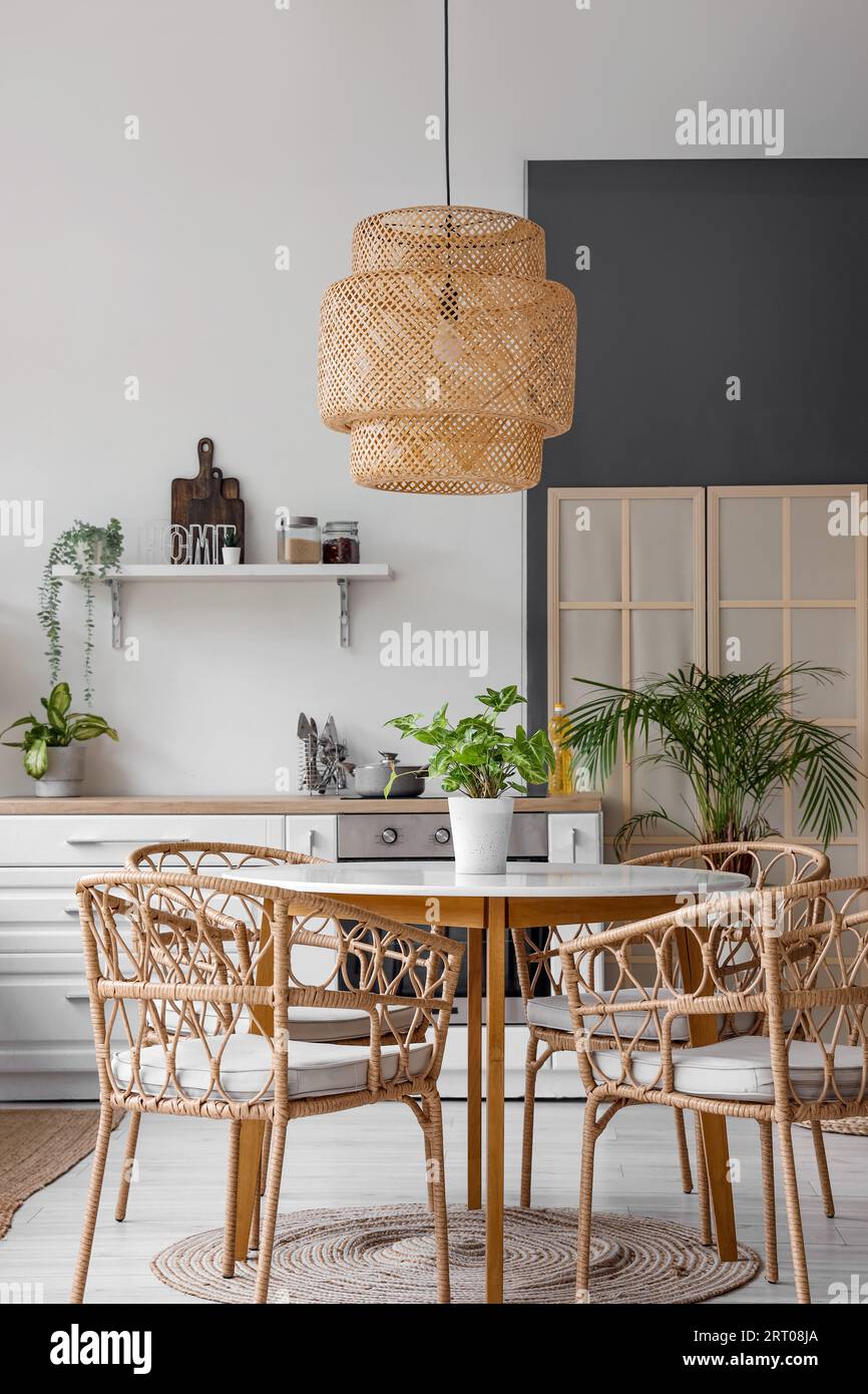 Interior of modern kitchen with dining table, white counters and wicker ...