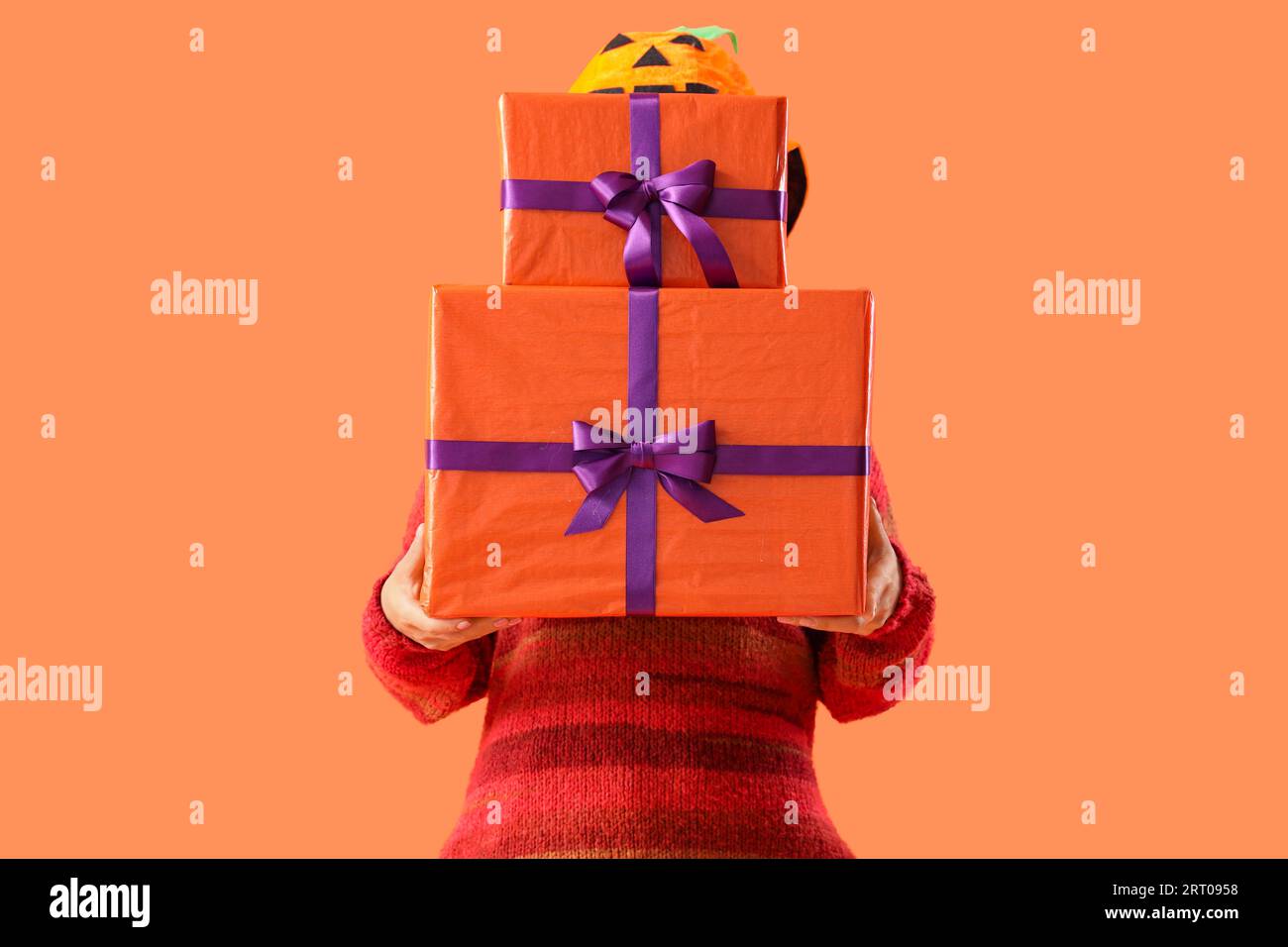 Young woman with Halloween gifts on orange background Stock Photo