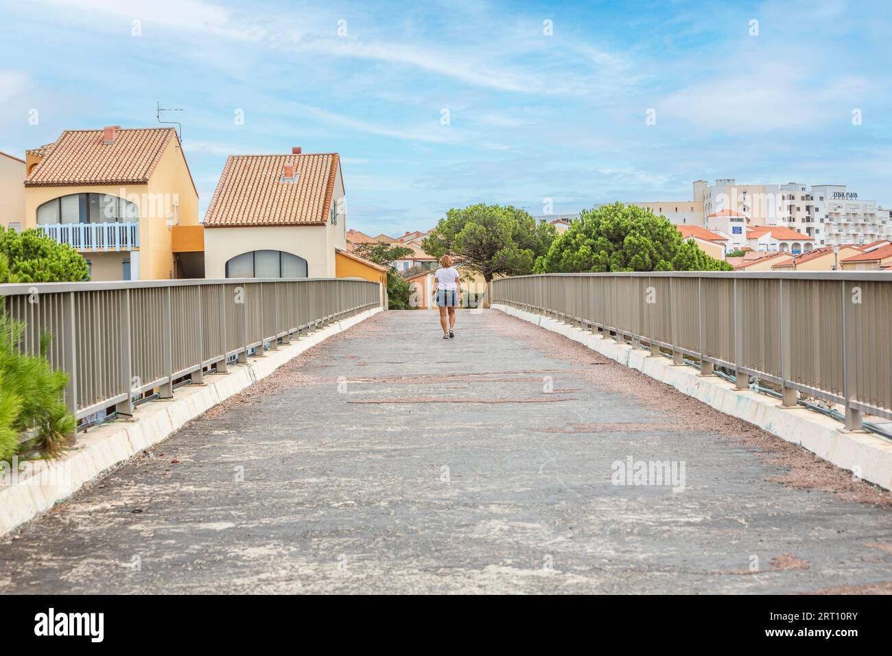 A lady walking over a pedestrian road bridge in Le barcares, South of France Stock Photo