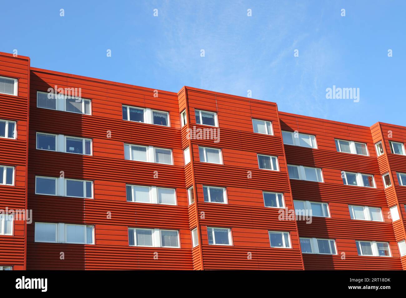 Exterior of a red colored multi-storey building with apartments built in the early 1970s. Stock Photo