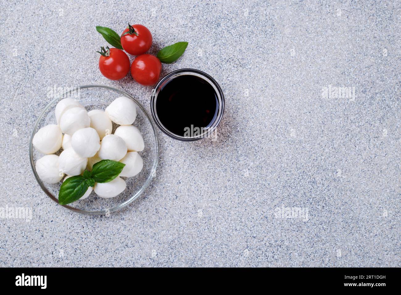Mozzarella cheese, basil and tomato cherry on grey stone table copy space. Ingredients for Italian Caprese salad Stock Photo