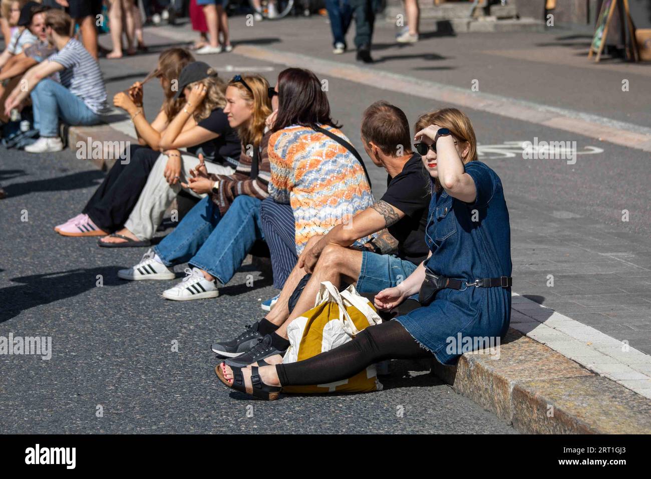 Young people sitting on a curb at Kallio Block Party 2023 in Helsinki, Finland Stock Photo