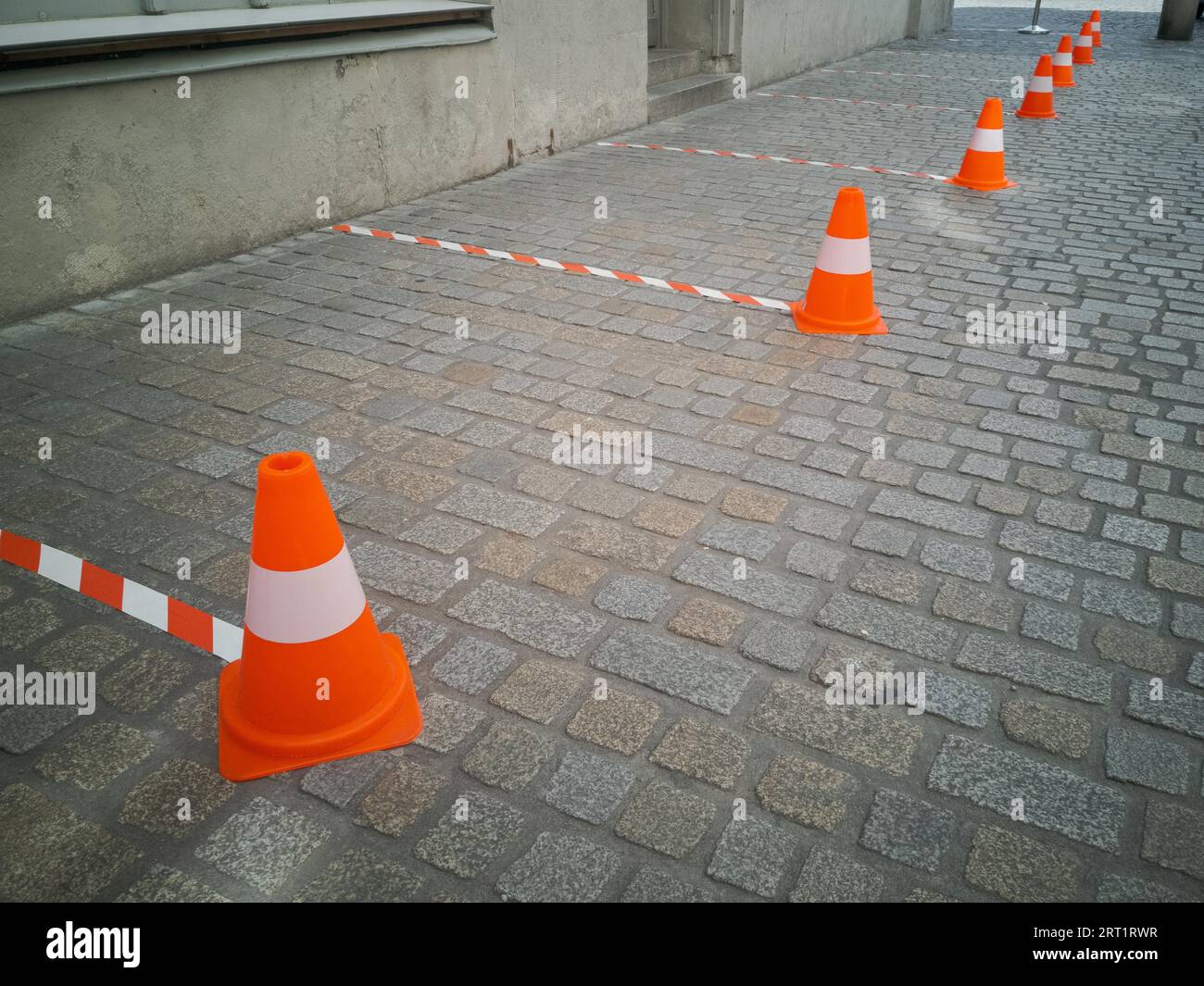 Six feet distance markings with barrier tape and traffic cones in front