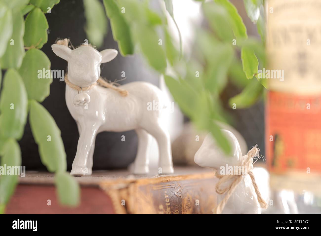 Close up of two small paschal easter lamb figurines made of white china standing on cupboard in living room with focus on left lamb Stock Photo