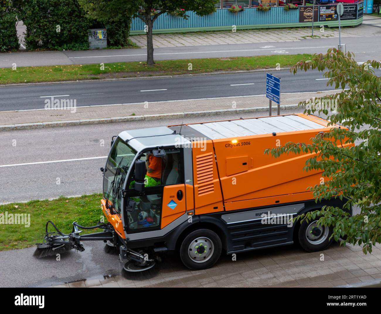 A Bucher Citycat 5006 sweeper, operated by the city of Vantaa, cleaning a sidewalk in Talvikkitie. Stock Photo
